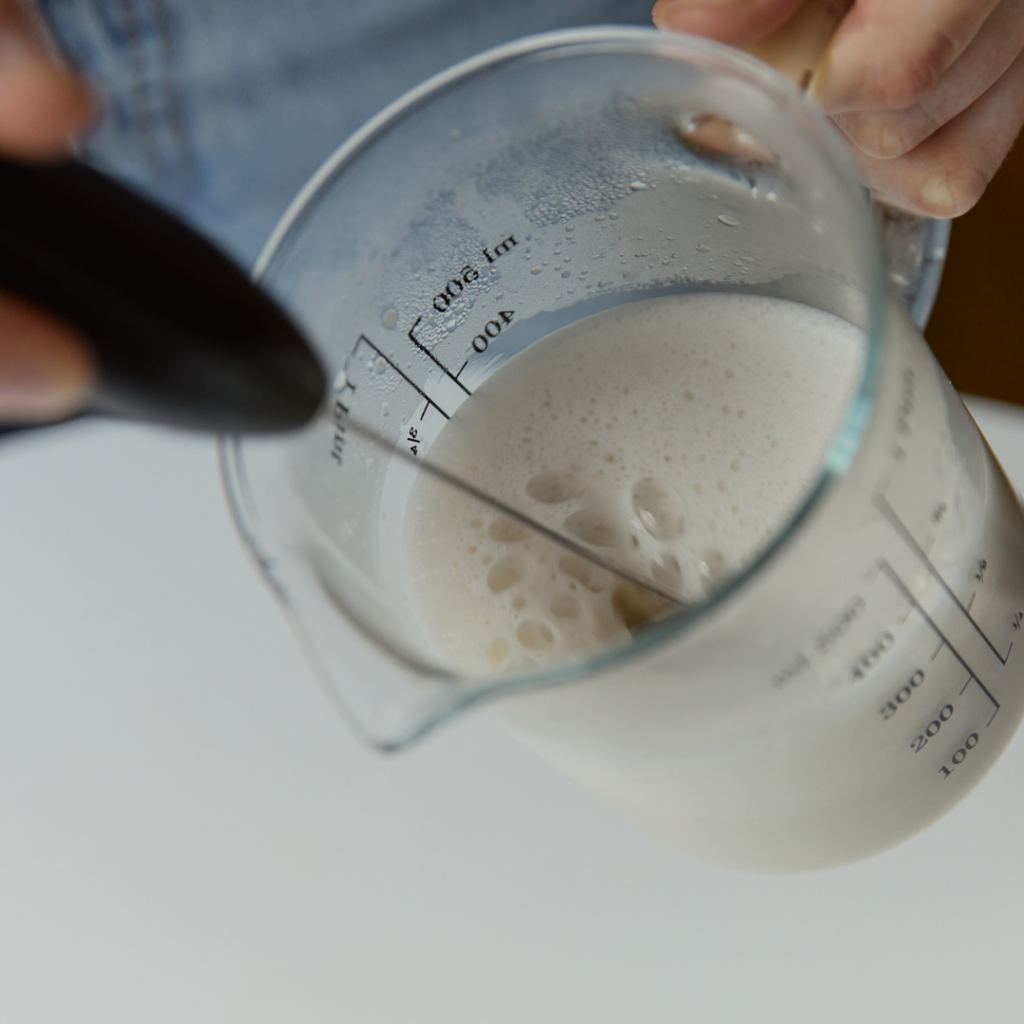A person using a hand held milk Frother